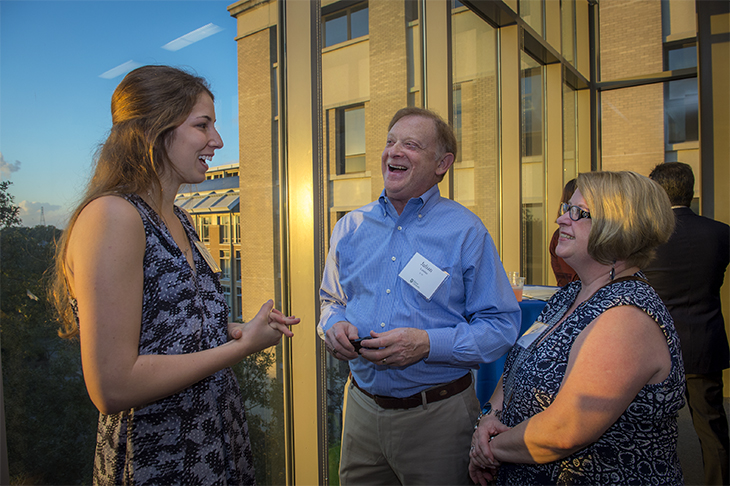 Madeline Sell, left, talks about her research with donors Julian and Julia Landau at an event